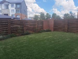 a wooden fence in front of a yard with a green lawn at Three Bedroom Apartment At The Blyde in Boschkop