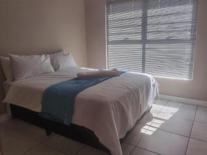 a bed in a room with a large window at Three Bedroom Apartment At The Blyde in Boschkop