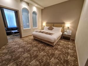 Gloria Hotel & Suites Doha في الدوحة: غرفة نوم بسرير واريكة ونوافذ