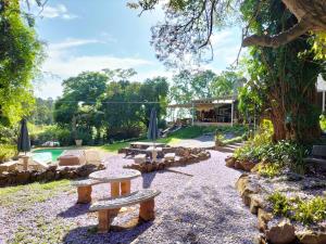 un jardín con 2 bancos y una piscina en ROCKABILLY RANCH Self-Catering Guest Units en Pietermaritzburg