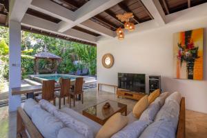 a living room with a couch and a table and a tv at Villa Lunacasa, Modern Comfort in Balinese Style, 500m to beach in Seminyak