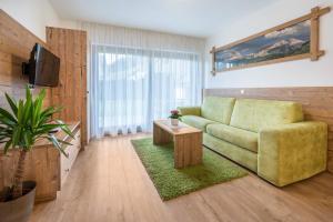 un salon avec un canapé vert et une télévision dans l'établissement Haus zur Vogelweide App 1, à Dobbiaco