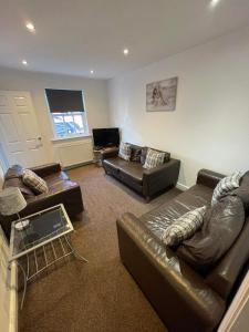 a living room with leather furniture and a flat screen tv at 2 Laurel Court in Ulverston