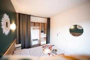 Dormitorio pequeño con cama y espejo en appartement n2 centre village, clim, parking gratuit, en Aigues-Mortes