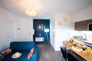 a living room with a blue couch and a kitchen at appartement n2 centre village, clim, parking gratuit in Aigues-Mortes +9 photos