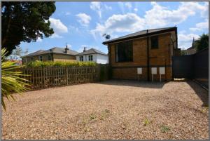 a house with a fence in front of a yard at Modern and cozy 2-guest flat with gated parking in Kingston upon Thames