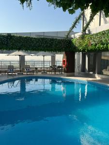 a large blue swimming pool with chairs and umbrellas at Gloria Hotel & Suites Doha in Doha