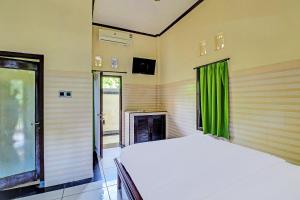 um quarto com uma cama branca e cortinas verdes em OYO 91925 Ijo Eco Lodge Hotel em Kapal