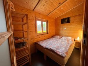 um quarto com uma cama num chalé de madeira em Chalet "Waldhauszeit" am See em Mücke