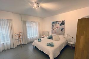 a bedroom with a large white bed and two windows at Apartment with free covered parking - City Center in Ghent