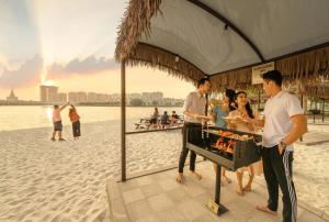 a group of people standing around a grill on the beach at Vinhomes Ocean Park Gia Lam by QMP in Hanoi