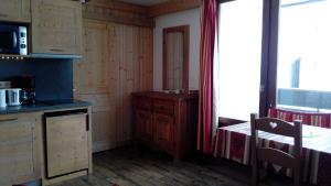 una cucina con armadi in legno, tavolo e finestra di Studio 20 Les Grandes Platières a Tignes