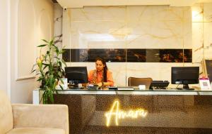 AMARA HOTEL في نيودلهي: امرأة تجلس في مكتب