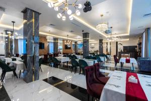 um restaurante com mesas e cadeiras brancas e lustres em Hotel Inspira-S Tashkent em Tashkent