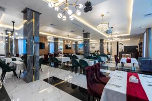 タシュケントにあるHotel Inspira-S Tashkentの白いテーブルと椅子、シャンデリアのあるレストラン
