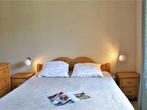 a bed with two pillows and a magazine on it at Appartement Risoul, 2 pièces, 6 personnes - FR-1-330-209 in Risoul