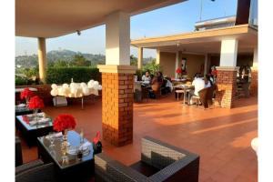 een patio met tafels en stoelen en mensen zitten bij Crystal Suites & Apartments in Kampala