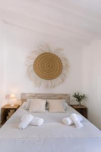 una camera da letto con un letto bianco e un cappello di paglia appeso al muro di VILASUITES Beach, Sand & Menta a Villajoyosa