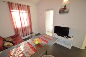 a living room with a television and a table at Apartments Milanović in Mali Lošinj