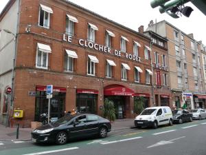 una macchina nera parcheggiata di fronte a un edificio di mattoni di Le Clocher de Rodez Centre Gare a Tolosa