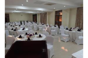 een kamer met witte tafels en witte stoelen en een kamer met witte tafels en wit bij Crystal Suites & Apartments in Kampala