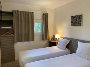 a hotel room with two beds and a window at Contact Hôtel Marseille Aubagne in La Penne-sur-Huveaune