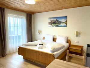 a bedroom with a large bed with white sheets at Haus Seerose in Seeboden