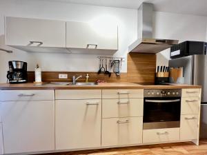 - une cuisine avec des placards blancs et un évier dans l'établissement Modernes Apartment mit besonderem Charme - 1A Guesthouse, 