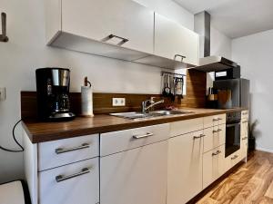 una cocina con armarios blancos y fregadero en Modernes Apartment mit besonderem Charme - 1A Guesthouse 