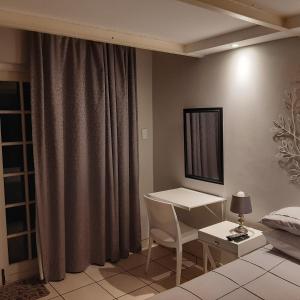 a bedroom with a desk and a bed and a table at The Cradle's Rest Guest House in Krugersdorp