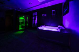 - une salle de bains sombre pourvue d'une baignoire avec un éclairage violet dans l'établissement B&B Palazzo del Toro, à Montesilvano