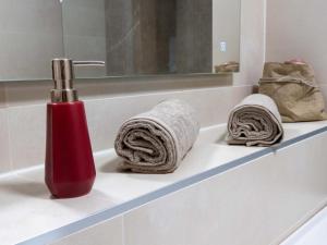 a red bottle on a bathroom sink with towels at Jagerwirt rooms in Völkermarkt