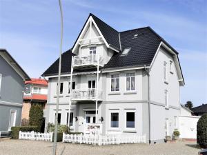 una casa blanca con techo negro en FeWo 1 "Birkenast" 1OG inkl Strandkorb, en Dahme