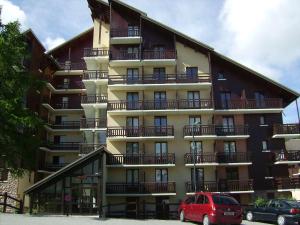 un edificio con balconi e un furgone rosso parcheggiato di fronte di Studio coin montagne calme, 4 pers, parking, Risoul 1850 - FR-1-330-92 a Risoul Altre 6 foto