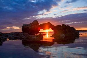 a sunset over the water with rocks in the water at Casa Tonino in Porto Cesareo