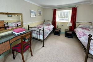 a bedroom with two beds and a desk and a mirror at Bonawe House Holiday Cottages in Taynuilt
