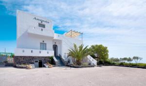 a white building with a palm tree in front of it at Anessis in Fira
