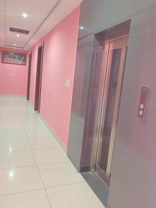un couloir avec des portes vitrées et des murs roses dans l'établissement Om hotel, à Rohtak 16 autres photos