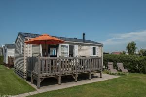 a house with a deck with an umbrella and chairs at Park Merlo in Bredene