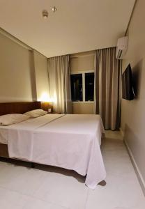 a bedroom with a large white bed and a window at Salinas Exclusive Resort - Apto 1Q in Salinópolis