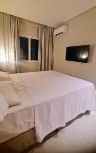 a large white bed in a room with a tv at Salinas Exclusive Resort - Apto 1Q in Salinópolis