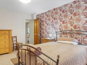 um quarto com uma cama com uma parede floral em Pass the Keys Cosy Home in the Idyllic Duddon Valley em Ulpha