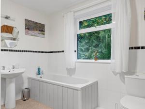 uma casa de banho branca com uma banheira, um lavatório e uma janela em Pass the Keys Cosy Home in the Idyllic Duddon Valley em Ulpha