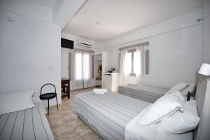 a white bedroom with two beds and a desk at Anessis in Fira