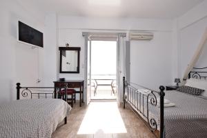 a bedroom with two beds and a desk and a window at Anessis in Fira