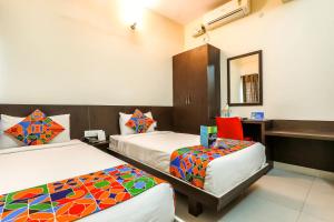 a hotel room with two beds and a desk at FabHotel RMS Comforts - Nr Yeshwantpur Railway Station in Bengaluru