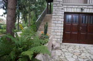 uma casa com uma porta de garagem de madeira e algumas plantas em Fenyves Vendégház em Bábolnapuszta