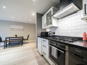 a kitchen with a stove top oven next to a table at Pass the Keys Stunning 2BR Apt w Balcony Views City Centre in Belfast