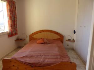 een groot houten bed in een kleine slaapkamer bij Appartement Le Lavandou, 2 pièces, 2 personnes - FR-1-308-35 in Le Lavandou
