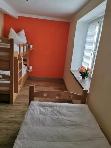 um quarto com paredes cor de laranja, uma cama e uma janela em Gästewohnung Schönfeld em Frohburg
